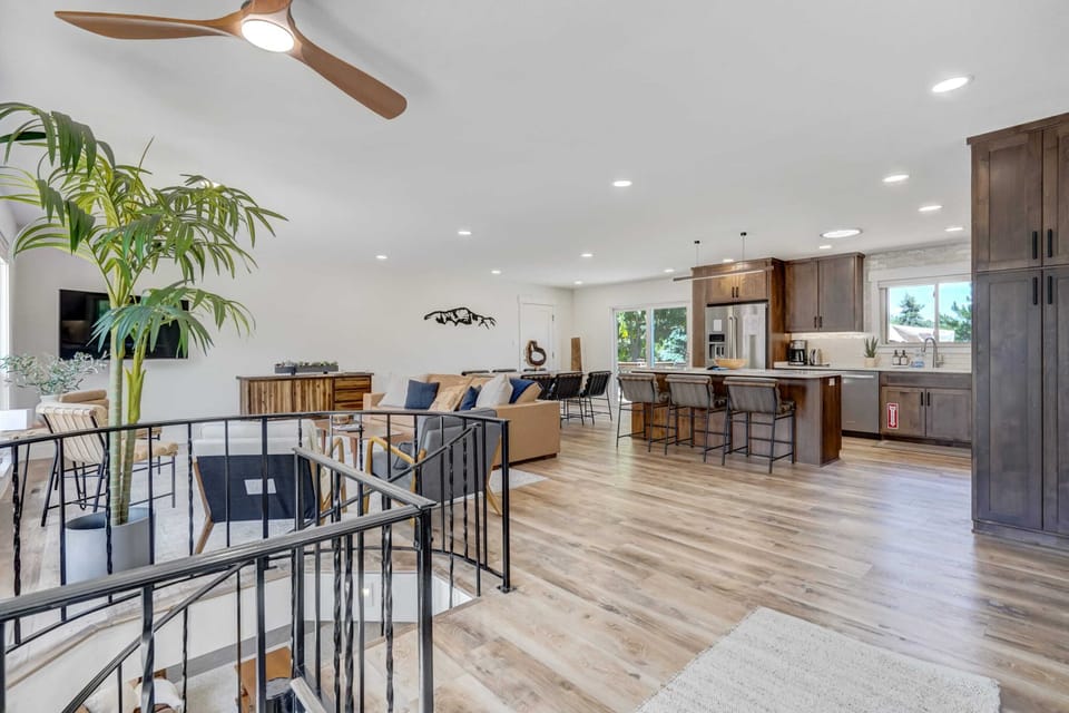 Sunlit open-concept space with a roomy kitchen island and bar stools—prep snacks, pour a drink, and keep everyone together from dining table to kitchen without missing a moment.