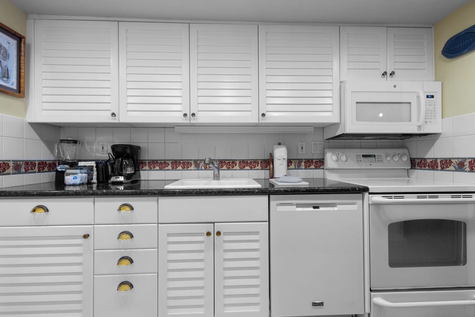 This well-equipped kitchen features white louvered cabinetry, stainless steel appliances, a coffee maker, blender, and everything you need to prepare your favorite meals in comfort.