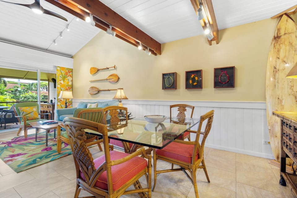Gather around your tropical-inspired dining table where warm island vibes meet modern comfort under vaulted beamed ceilings. Relax with garden views while colorful art and unique details make every meal memorable.