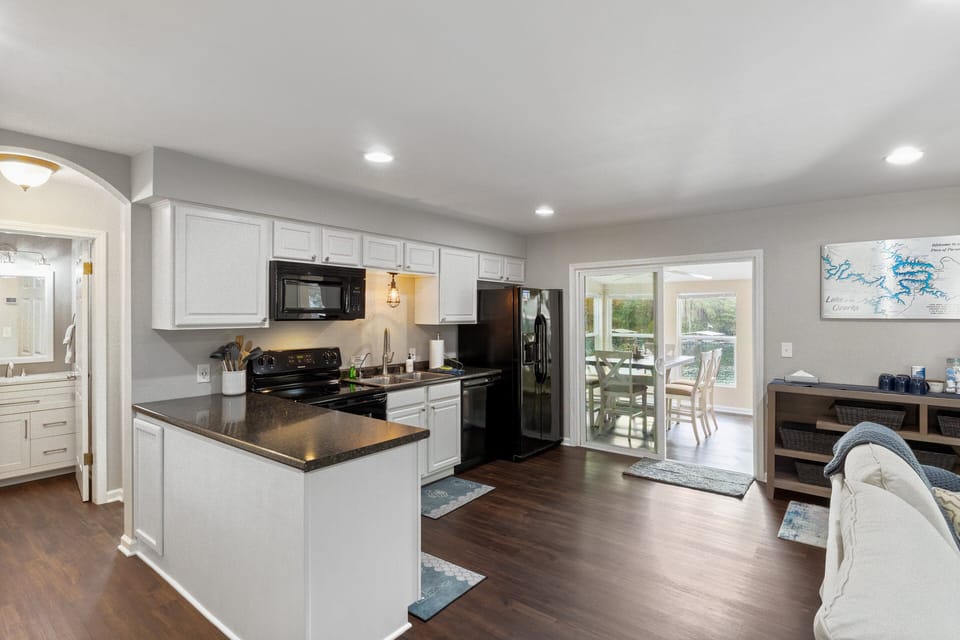 Fully equipped kitchen with modern appliances, a cozy dining area, and easy access to a sunroom with lake views.