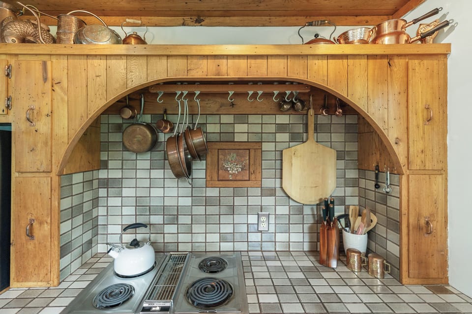 Custom Pecky-Cypress wood cabinets in the kitchen with Carrera marble accents