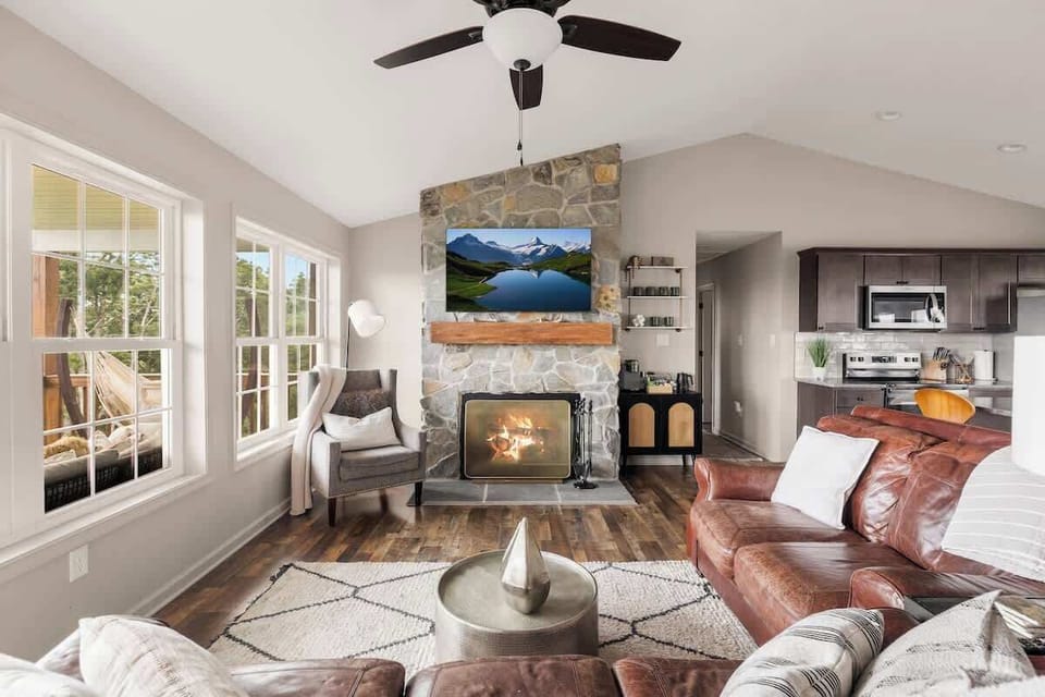 Living room with cozy fireplace, vaulted ceiling, and leather sectional