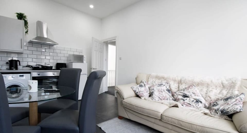 Central to the lounge find a glass round dining table with 4 grey chairs.