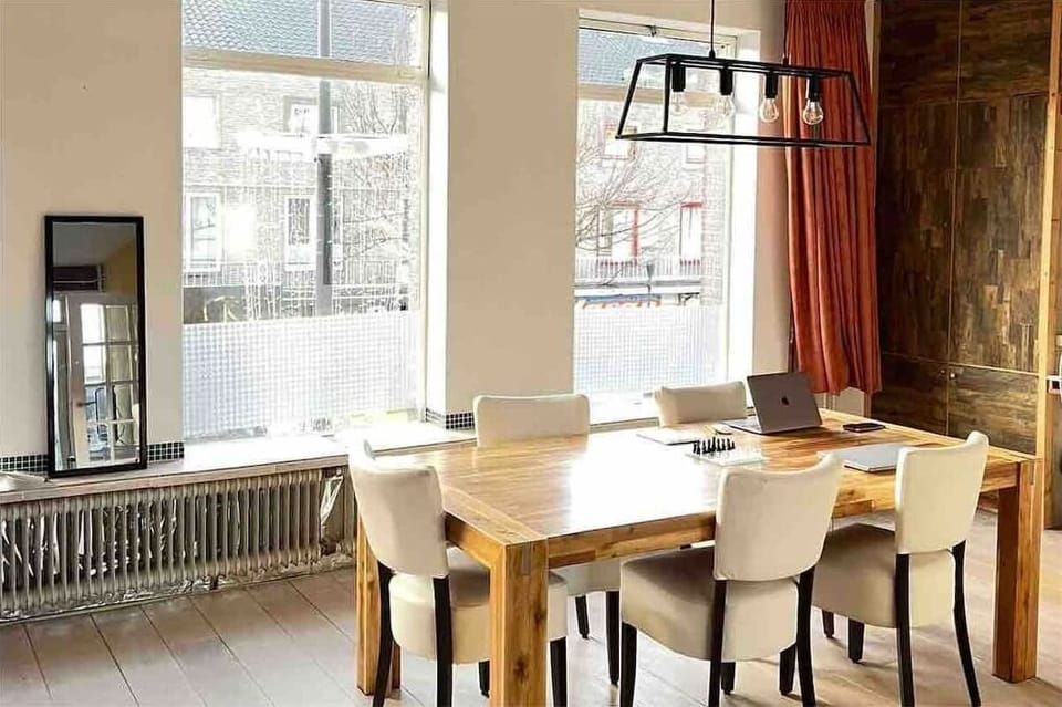 Modern dining area with a large wooden table and natural light from tall windows