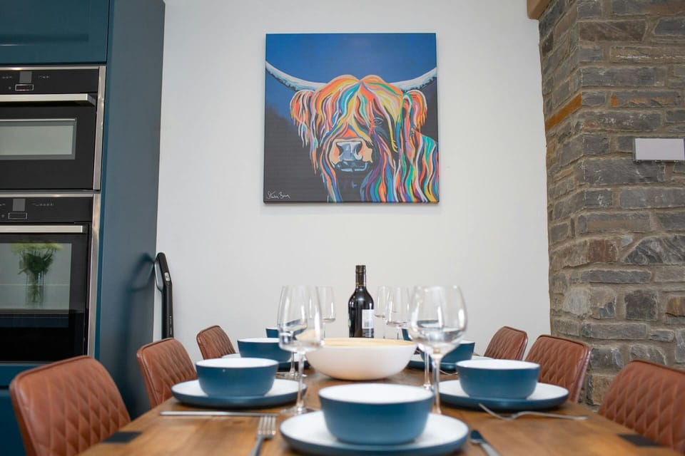 Dining table laid for dinner and large piece of art on  the wall