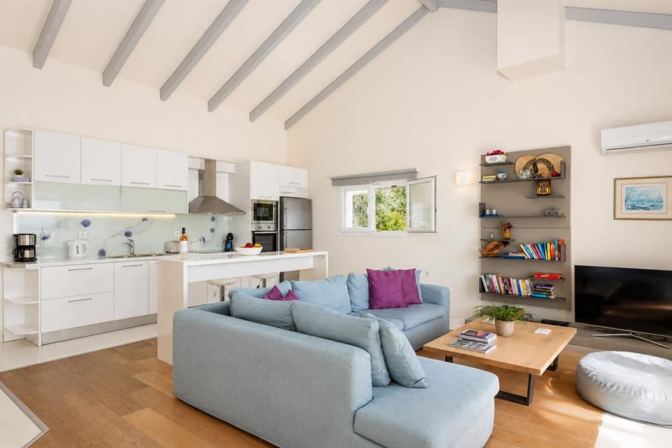Open-plan living room with sofa, dining area, kitchen, A/C, WiFi internet, and satellite TV