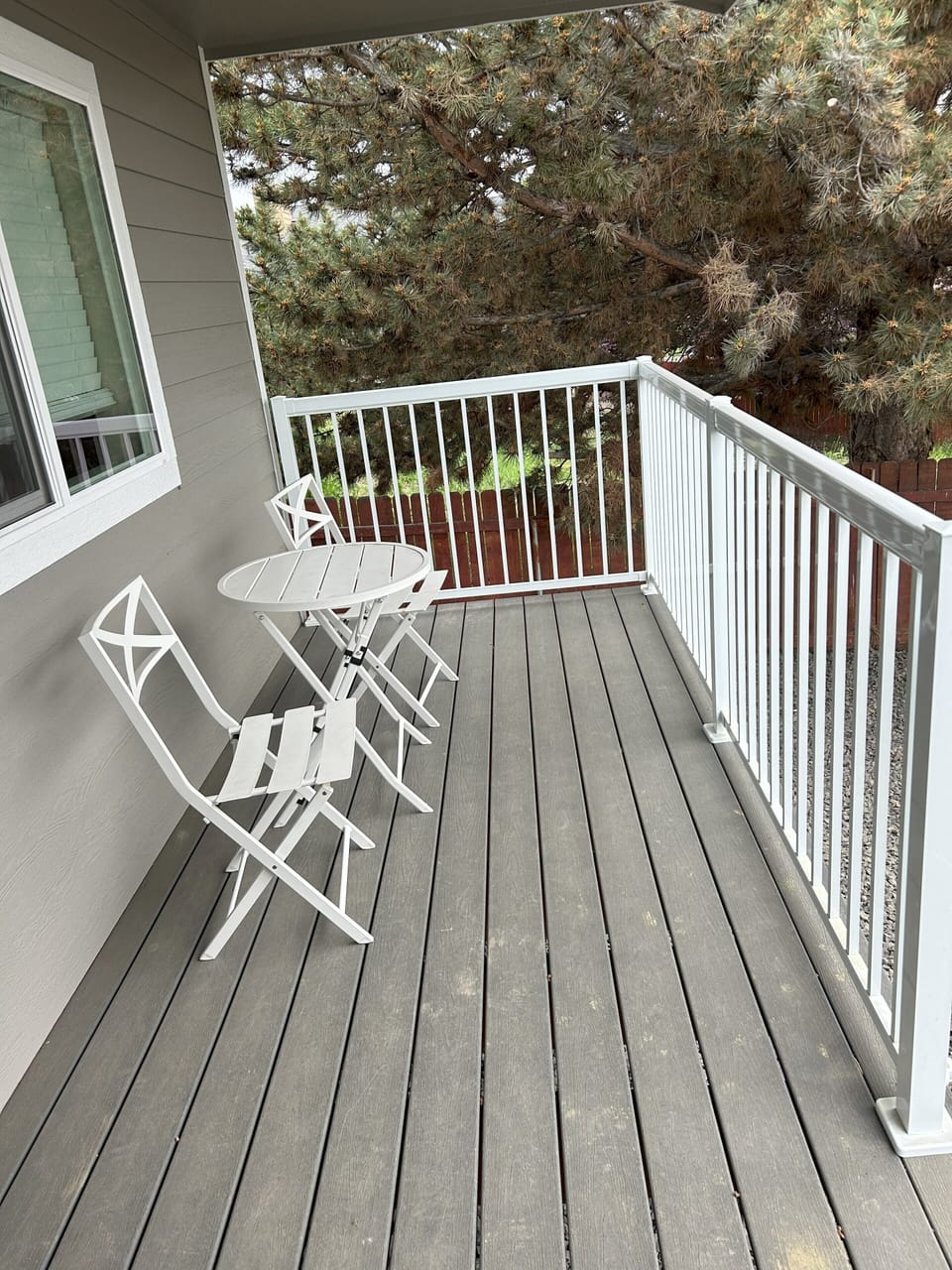 Backyard patio deck with two chairs and a table.