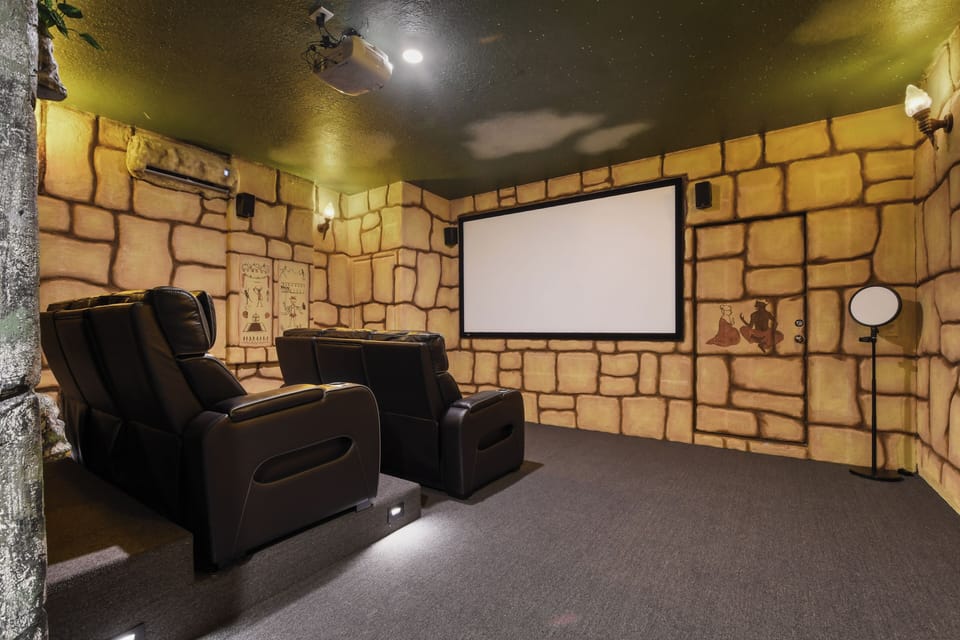 Stone-walled home theater with recliners and a giant screen!