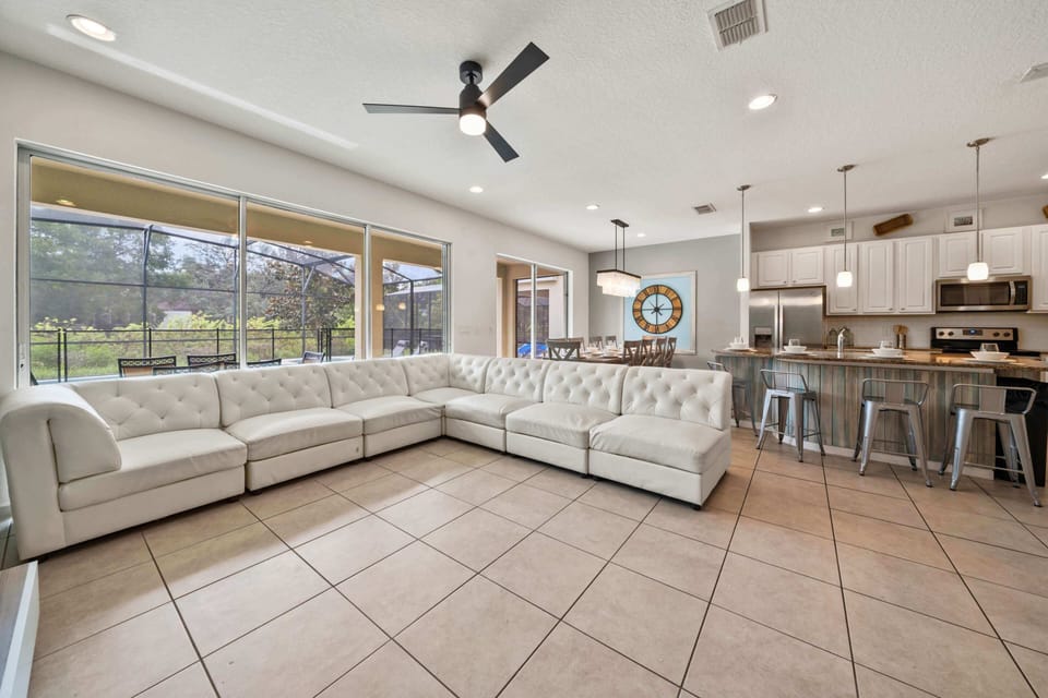 - Spacious living area with sectional sofa and open-concept design  
- Large windows bring natural light and pool views indoors  
- Perfect gathering spot in this Orlando vacation rental home