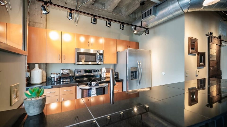 Modern kitchen with stainless steel appliances, sleek countertops, and industrial-style accents, perfect for preparing meals in style.