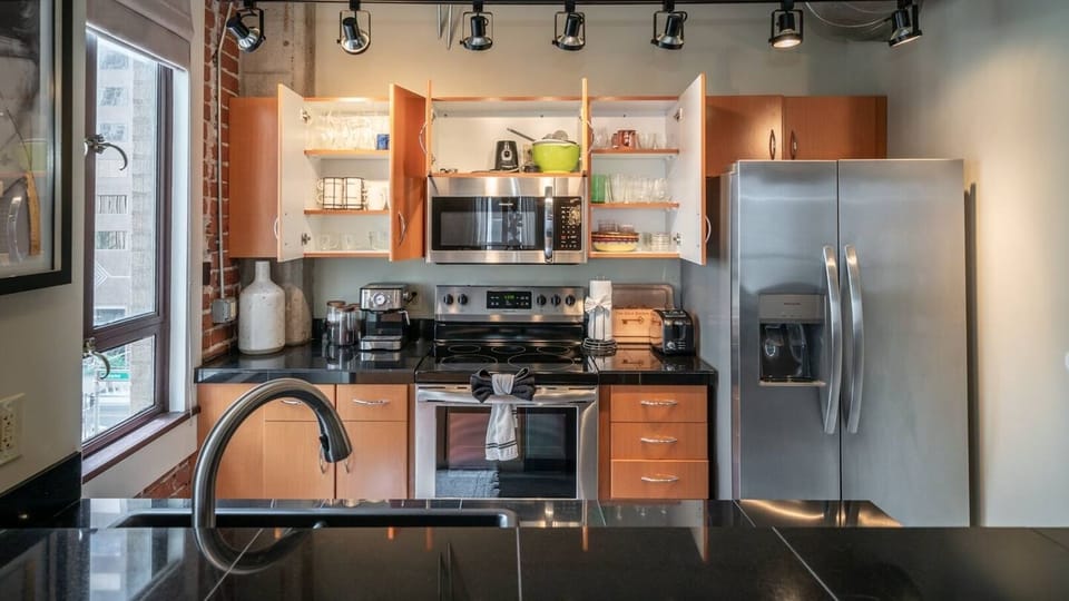 Modern kitchen with stainless steel appliances, sleek countertops, and industrial-style accents, perfect for preparing meals in style.