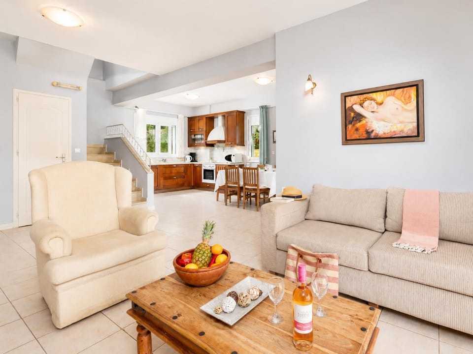 Open-plan living room with sofa, dining area, kitchen, ornamental fireplace, A/C, WiFi internet, and satellite TV