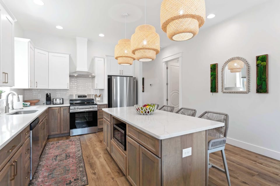Modern kitchen w/ island seating, warm wood tones & stylish lighting