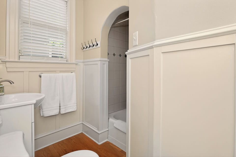 Main level full bathroom with door to bedroom and hallway by kitchen