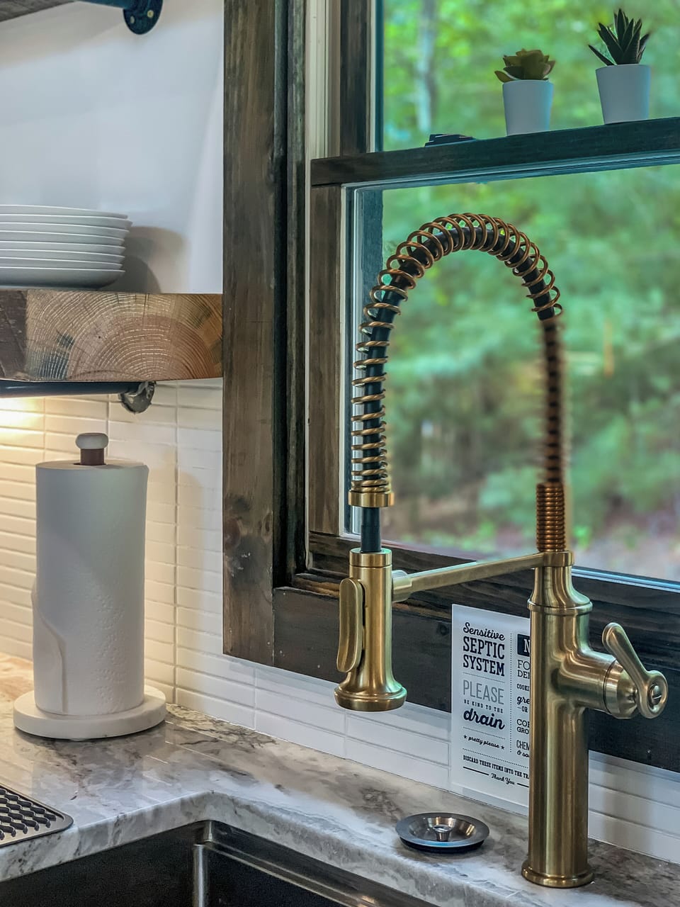 A close-up of a sleek, modern kitchen faucet with a brass finish.