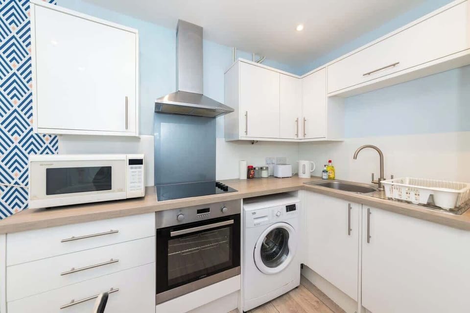 Cook with ease in this sleek kitchen featuring an oven, microwave, washing machine, and all essential cookware—perfect for long stays or home-cooked meals on the go.