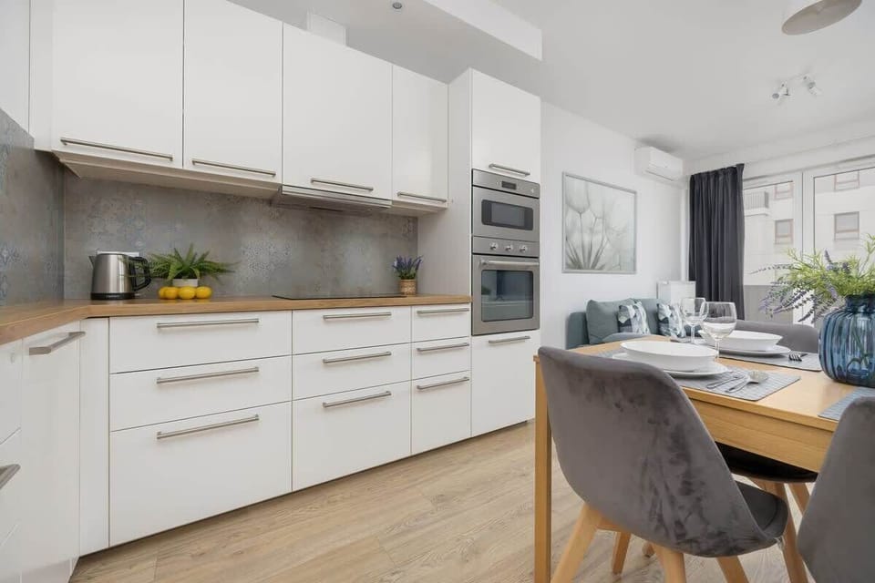 Modern kitchen with white cabinets and a central wooden dining table.