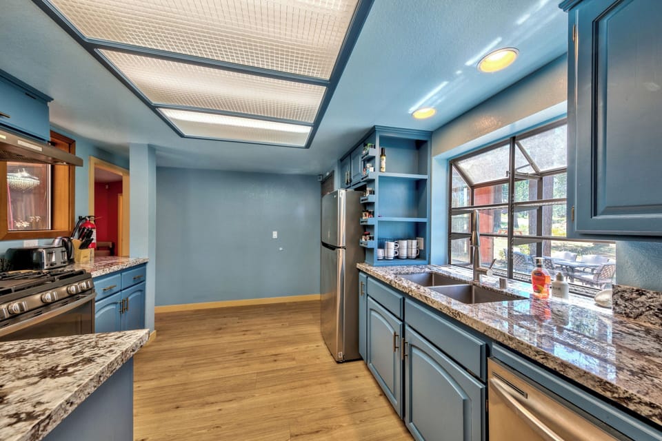 Cook your favorite meals in this spacious blue kitchen featuring granite counters, stainless appliances, and a bright skylight overhead.