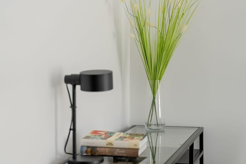 A close-up shot of the work desk with a lamp and decorative grass in a glass vase.