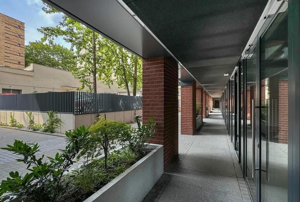 Covered outdoor corridor or balcony area with greenery and modern architecture.