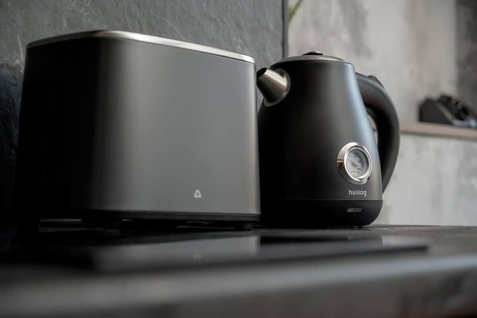 In this minimalist kitchenette, a sleek black countertop is accented by a kettle and toaster, ideal for quick morning routines.