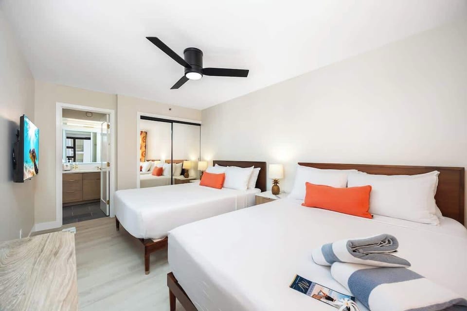 This bedroom features 2 cozy Queen beds, storage with mirrored closet doors, a mounted 40" Sony TV for relaxing, and direct access to your modern private bathroom!