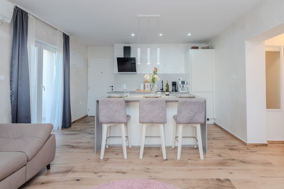 Open concept living room and kitchen, with stylish dining area for 3 guests. 
