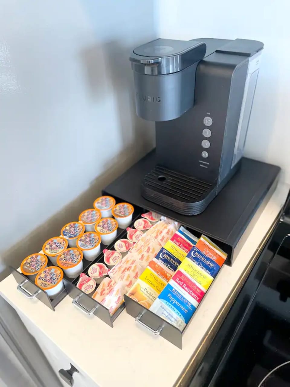 Keurig machine with coffee pods, sugar, creamers and variety of teas.