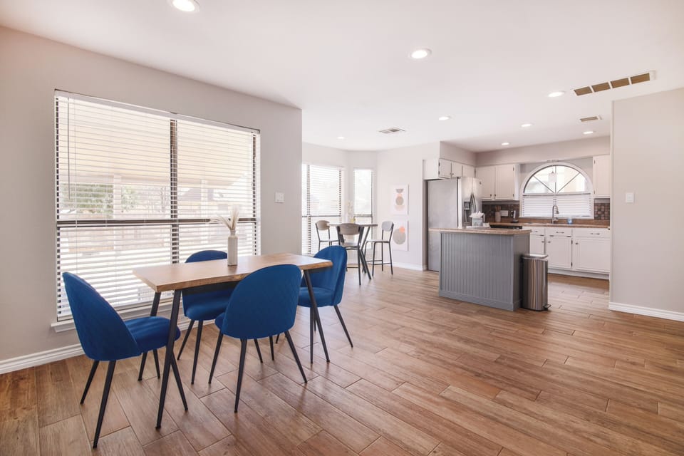 This modern dining area offers elegant seating and a small table by the windows, ideal for intimate meals. A second table near the kitchen enhances the flow, blending style and functionality for a cozy, inviting atmosphere.