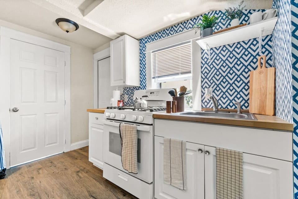 Fully equipped kitchen with a full-size refrigerator, stove, oven, microwave, cookware, dishes, utensils, and cooking essentials