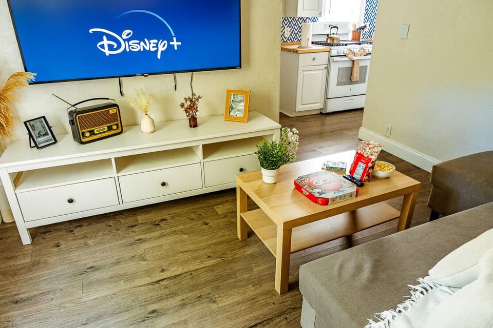 Bright and comfortable living room with a large Smart TV, streaming apps, high-speed Wi-Fi, and cozy seating.