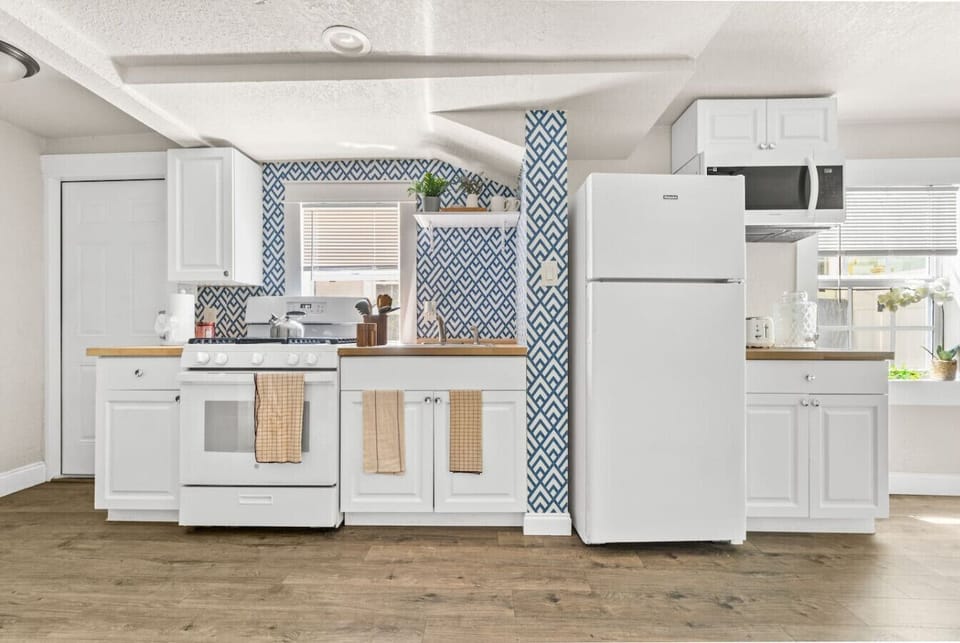 Fully equipped kitchen with a full-size refrigerator, stove, oven, microwave, cookware, dishes, utensils, and cooking essentials