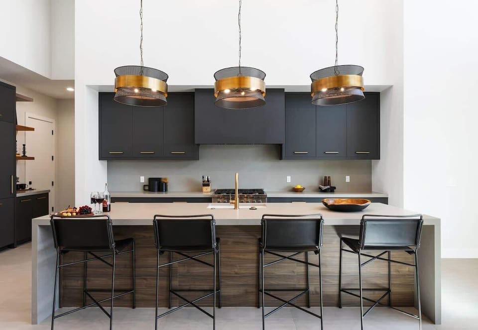 Unit 2: Fully equipped kitchen boasting high-end stainless steel appliances and a large island offering bar seating overlooking the formal dining area.