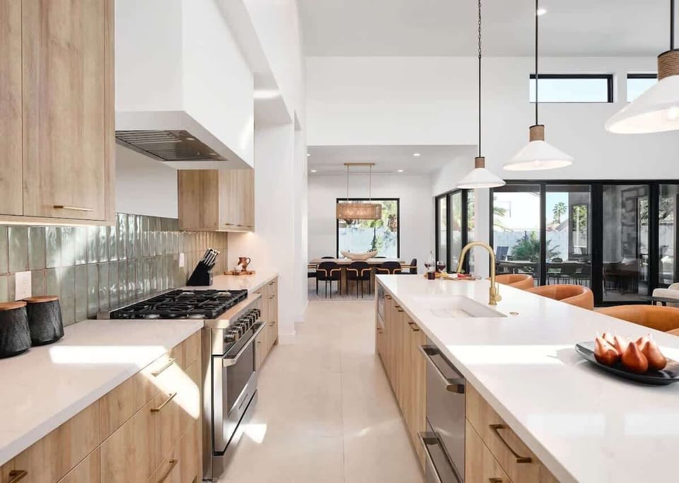 Unit 1: Fully equipped kitchen boasting high-end stainless steel appliances and a large island offering bar seating overlooking the formal dining area.