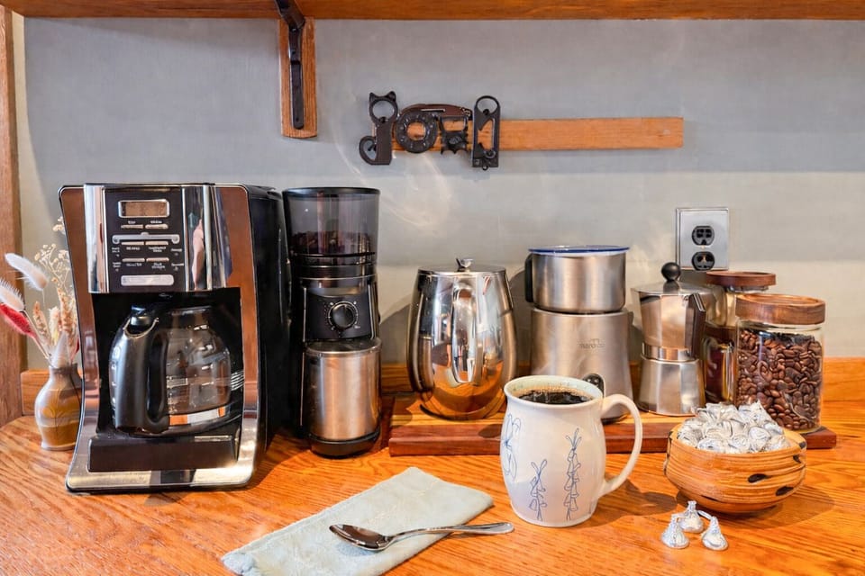 Gourmet coffee bar with grinder, fresh coffee beans, moka pot, milk frother and multiple brew options.