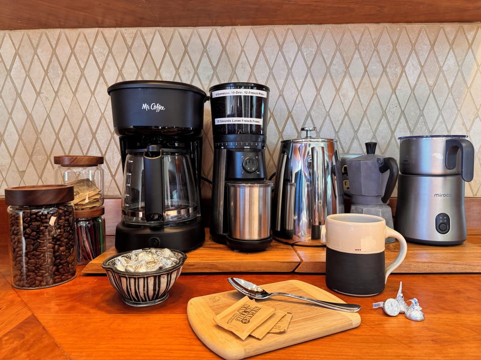 Barista-ready coffee nook: French press, preset burr coffee grinder, drip machine, moka pot for espresso, fresh beans, frother, and on demand hot water dispenser.