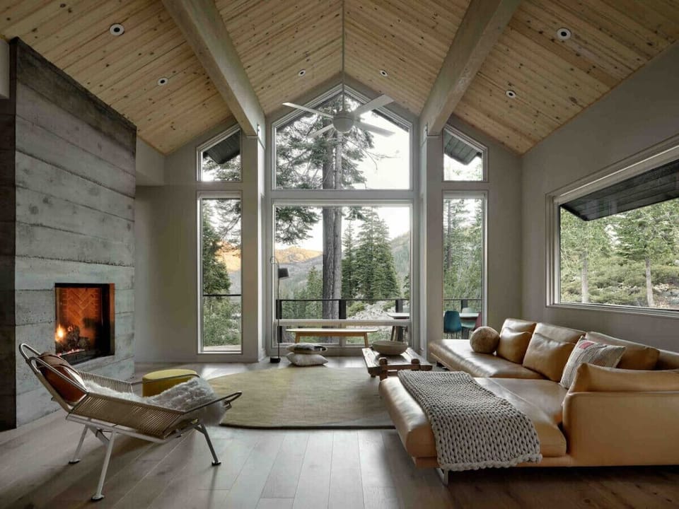 Cozy evenings by the fire in our open‑air living space, framed by soaring windows.