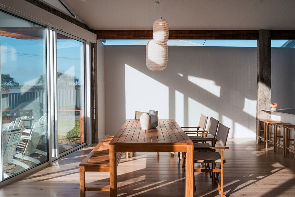 The space is adorned with stylish pendant lights and has a sleek, minimalist design with a light wooden floor and white walls, creating a bright and airy atmosphere.