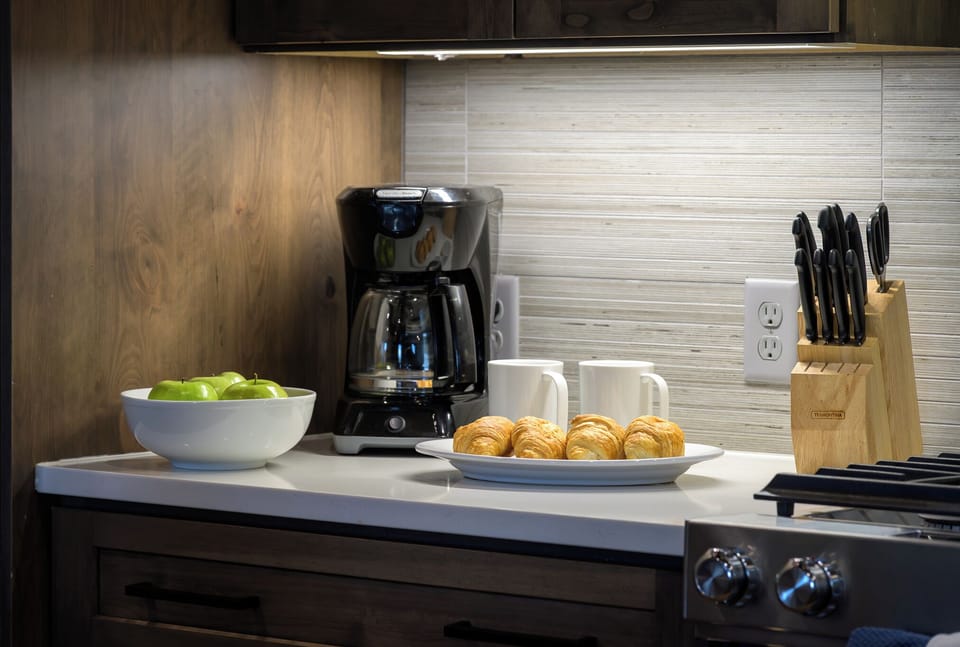 Wake up to a fresh cup at this cozy coffee station complete with mugs and drip brewer - Bowl of crisp green apples and flaky croissants invite a nourishing morning ritual