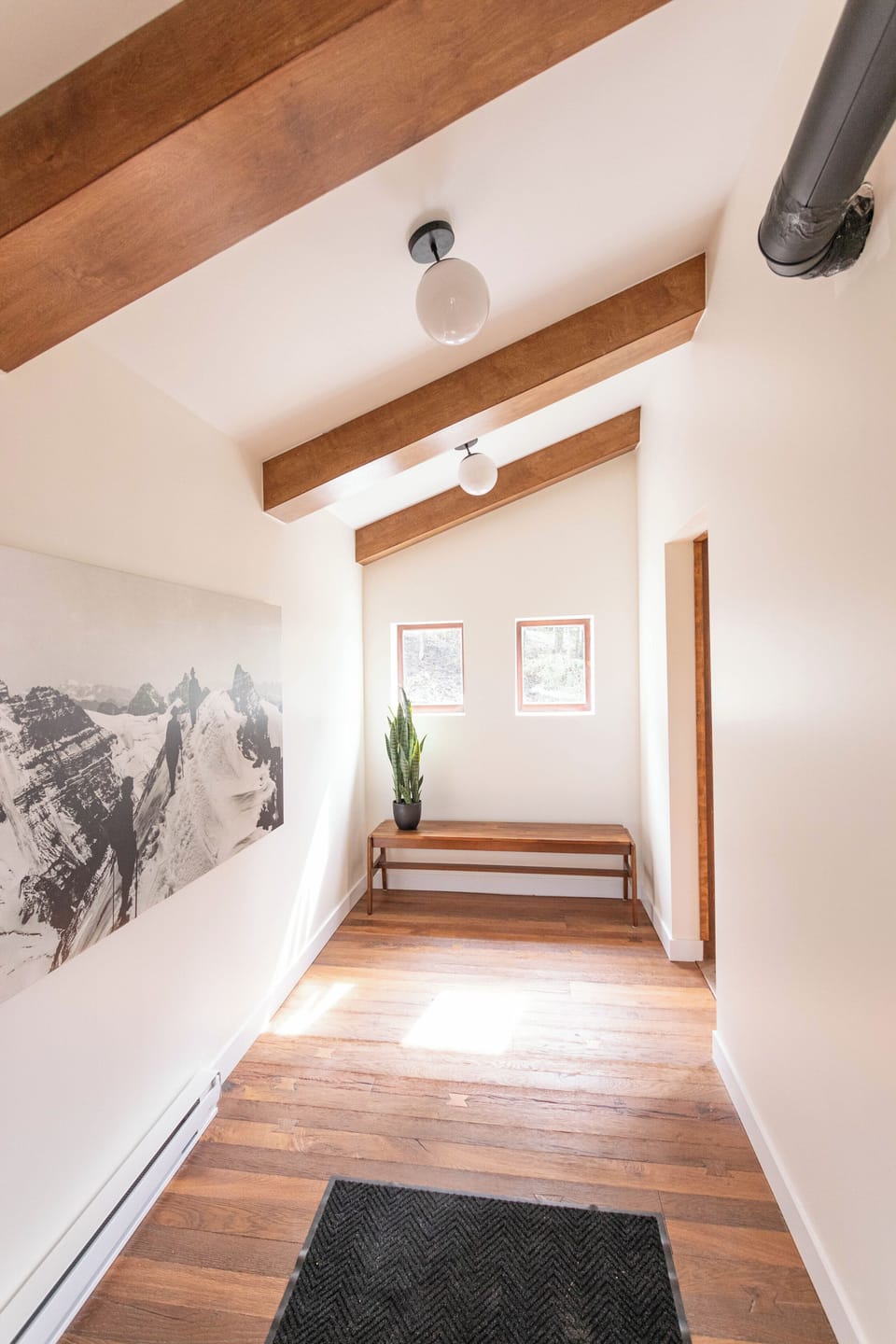 Step into this bright hallway adorned with rustic wooden beams and a touch of greenery.
