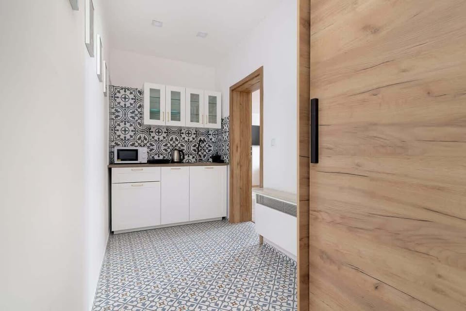 Bright kitchenette entrance with patterned flooring and white cabinetry welcoming you into the space.