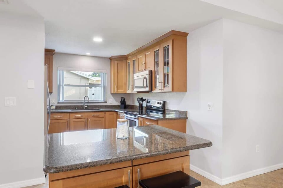 {KITCHEN} The open kitchen, seamlessly connecting to the living and dining areas, includes a spacious island, French door fridge, stove/oven, dishwasher, coffee maker, and all the essentials for cooking and enjoying meals.