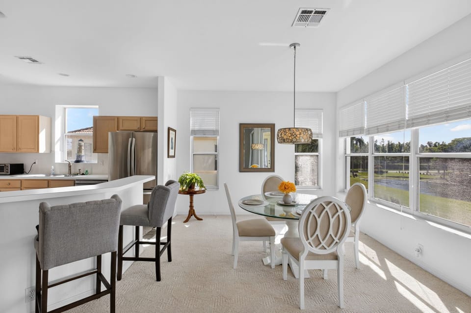 Open dining and kitchen area, with seating, a decorative pendant light, and views of lake and golf course..