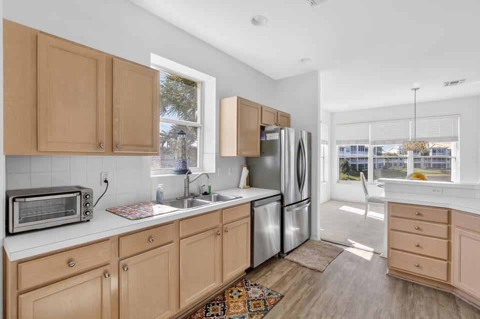 Kitchen features stainless steel appliances, plenty of counter space, and natural light through large windows.