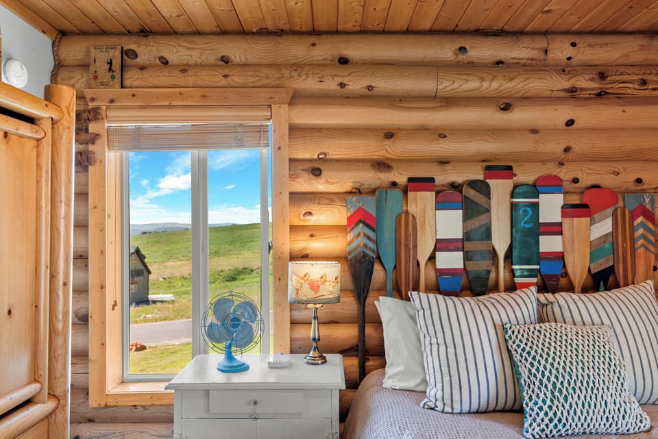 Relax in rustic charm! Cozy up in this log cabin bedroom featuring a comfy queen bed and Bear Lake-inspired paddles