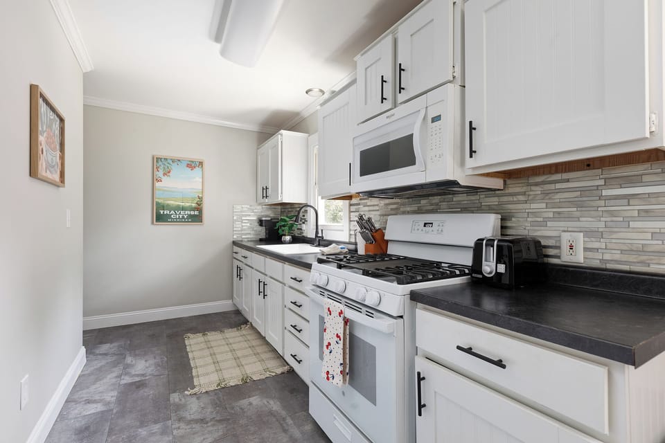 A bright and airy kitchen featuring white cabinets, stainless steel appliances, and a perfect blend of vintage charm with modern amenities.