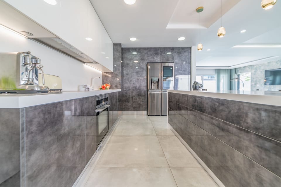 Modern galley kitchen with grey cabinetry and stainless steel appliances — Villa Alva, luxury holiday villa in Aroeira