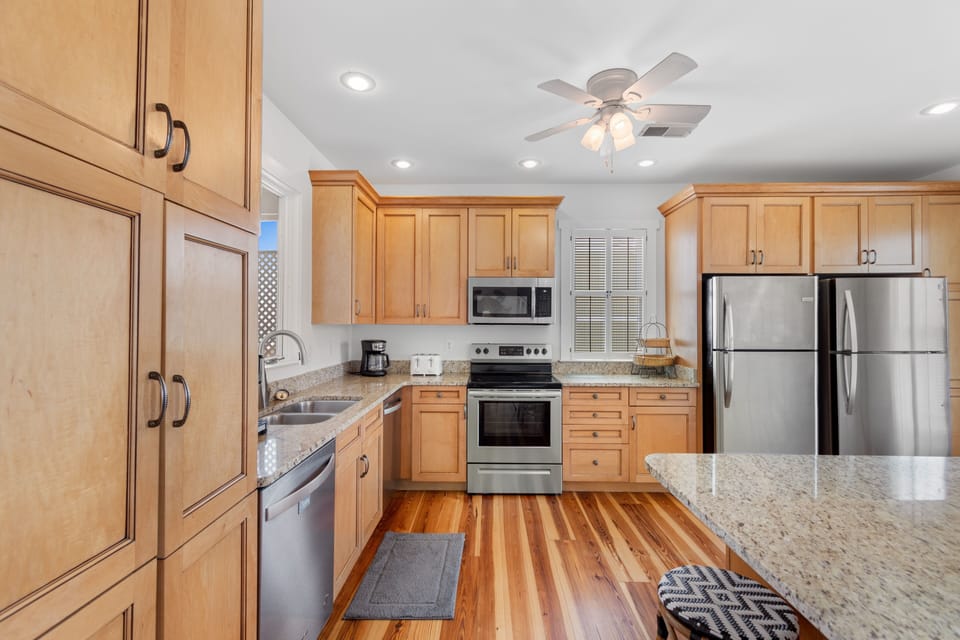 Your fully equipped kitchen awaits with granite counters, stainless appliances, and warm wood floors - perfect for preparing meals together.