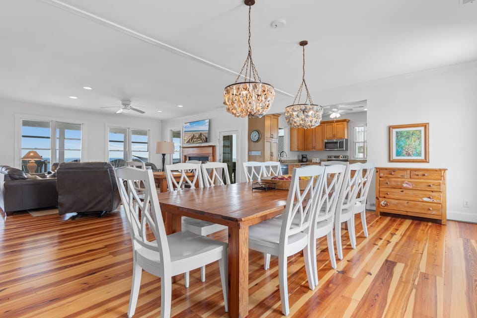 Gather around your elegant dining table under sparkling chandeliers, where polished hardwood floors and ocean views create the perfect setting for memorable meals.