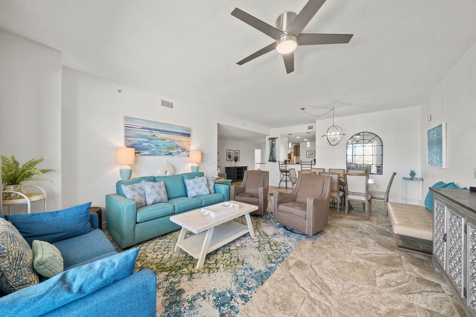 Step into your bright, open living space with vaulted ceilings, coastal décor, and a ceiling fan to keep you comfortable year-round as you unwind on plush seating.